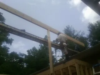 Carpenter setting a ridge beam over a new addition frame — Ice Dam Removal by Roofing Brothers in Longbranch