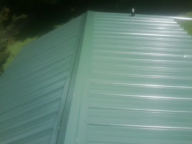 New green metal panels meeting at the ridge of a roof — Flat Roof Repair work by our crew in Longbranch