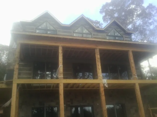 Dormers and porch framing on a large log home under construction — Roof Coating work by our crew in Longbranch