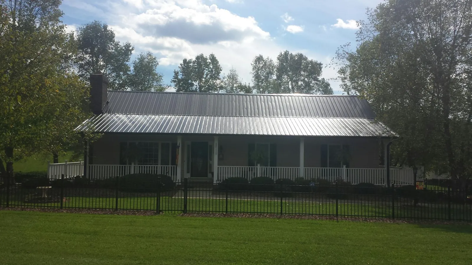 Gray metal roof on a brick ranch with a full width front porch — Gutter Guard Installation work by our crew in Longbranch