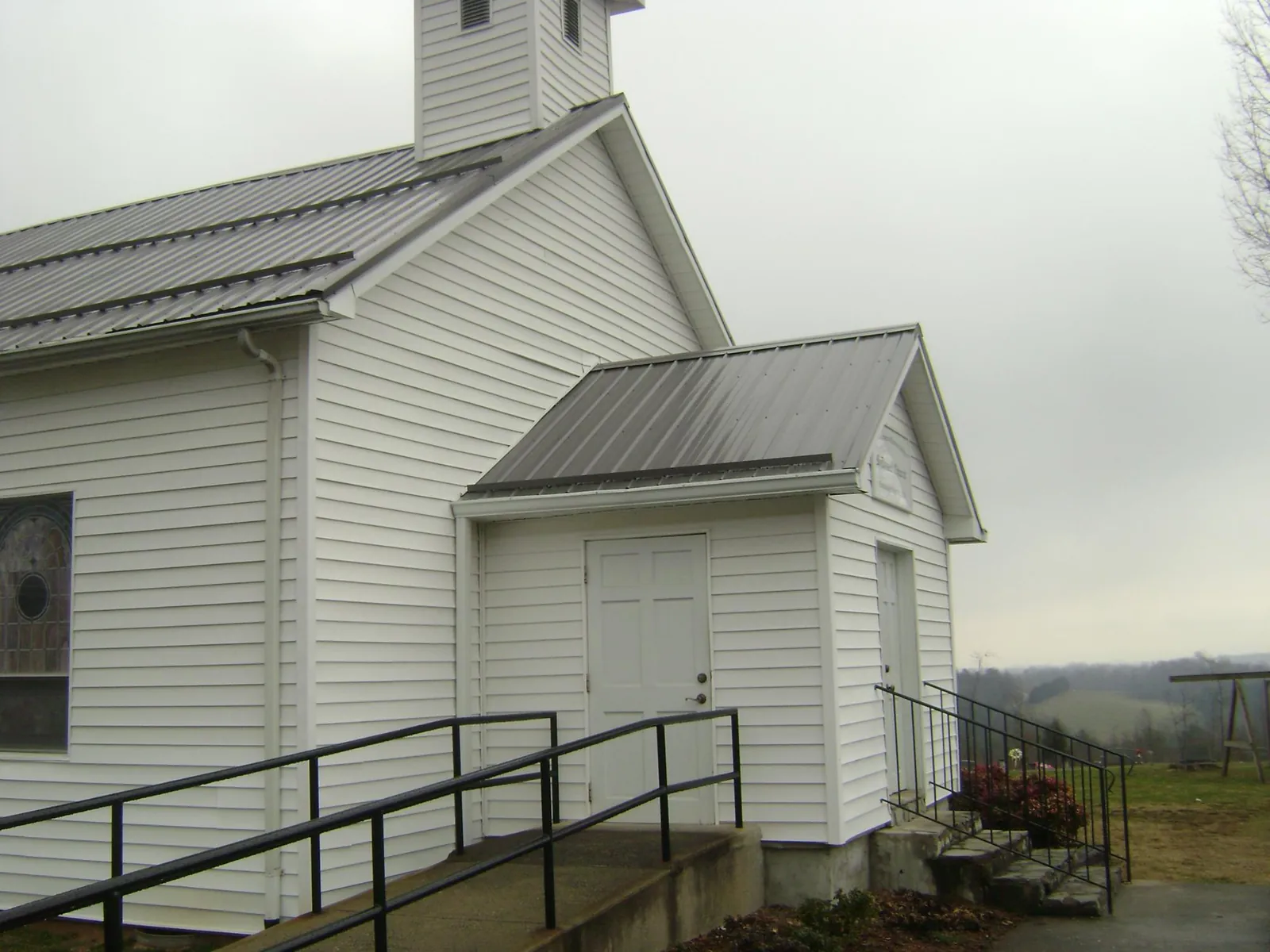 Gray metal roof on a white clapboard church with a steeple in Longbranch