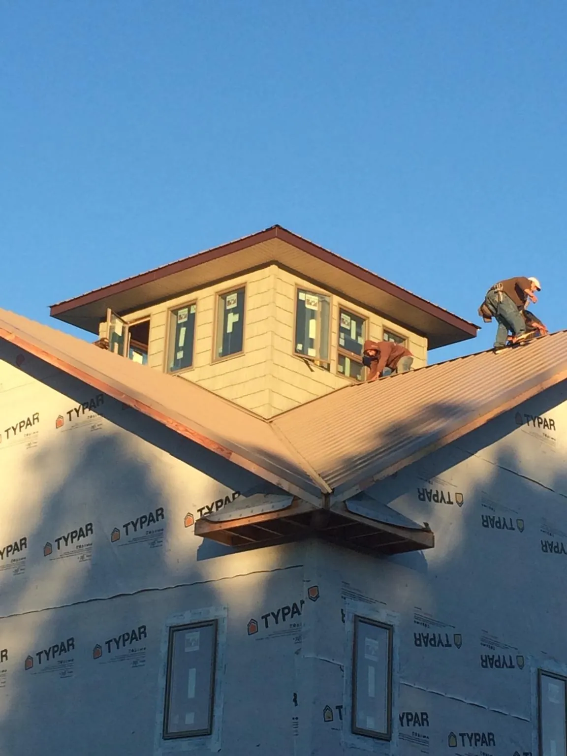 Roofers working around a rooftop cupola on a new metal roof at sunset — Roof Waterproofing in Longbranch by Roofing Brothers